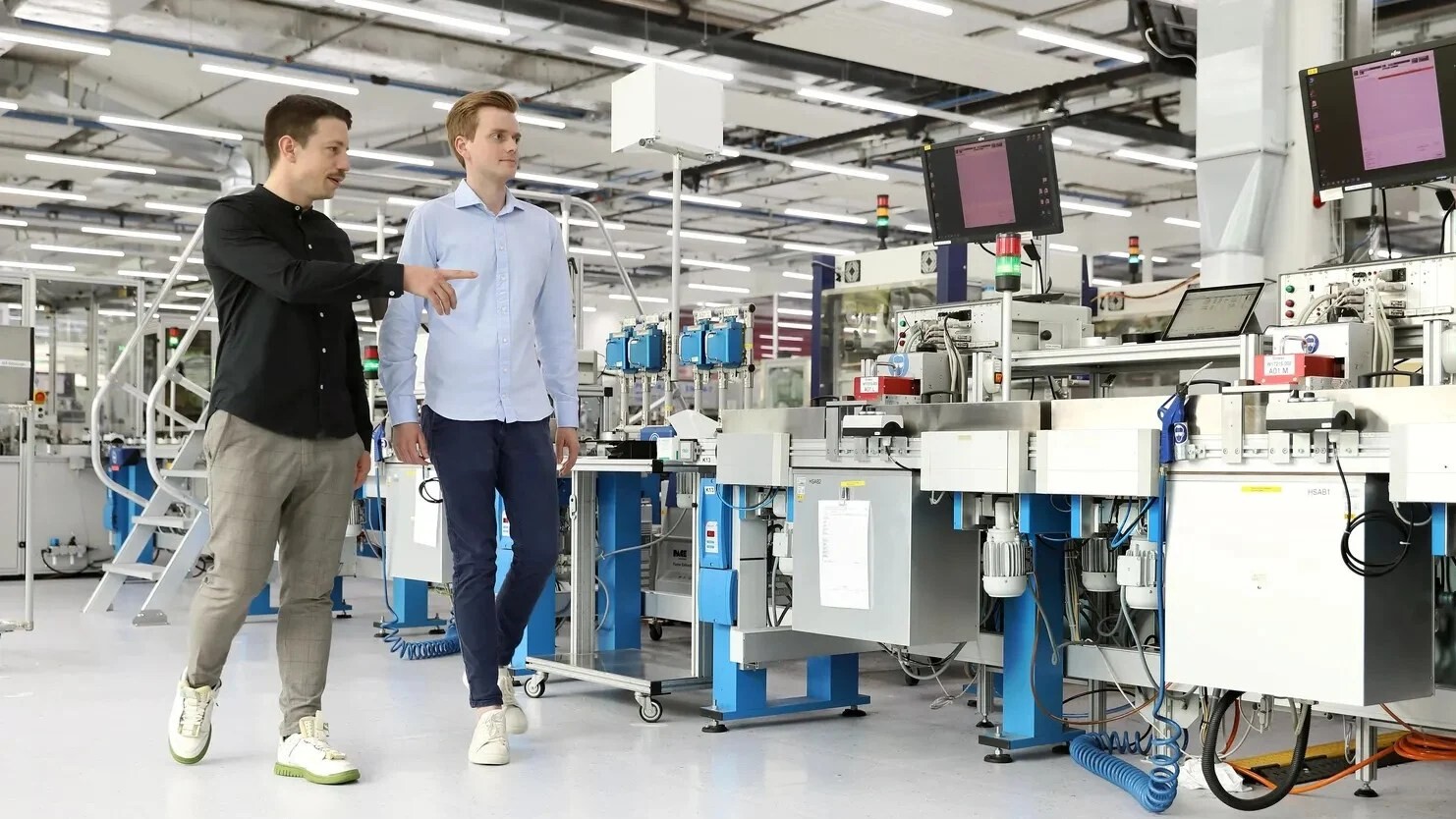 Bernhard Kratzwald and Julian Senoner walking beside production equipment in a Siemens factory