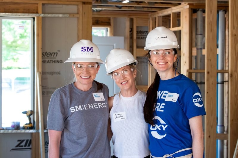 Beth McDonald, at left, with two fellow volunteers wearing hard hats at the home build