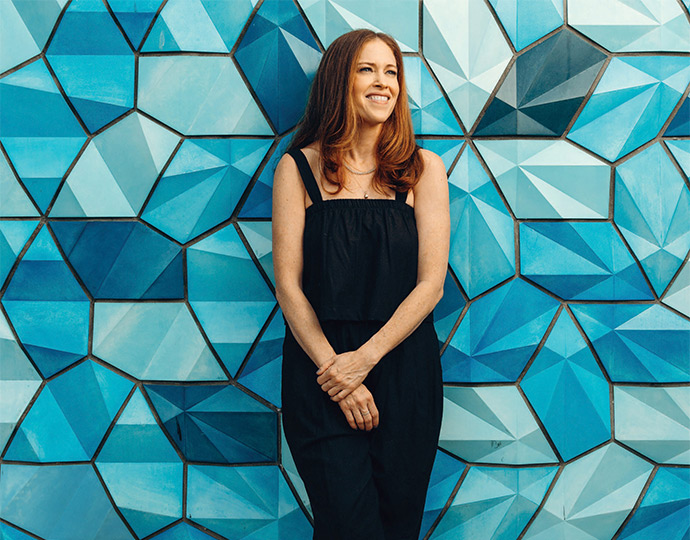 Beth Silverman standing in front of a blue geometric mural