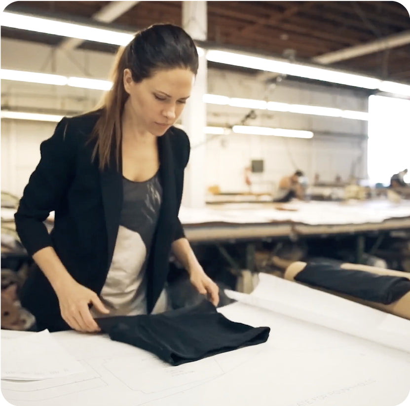 Betsie Larkin examining a black garment at a manufacturing worktable