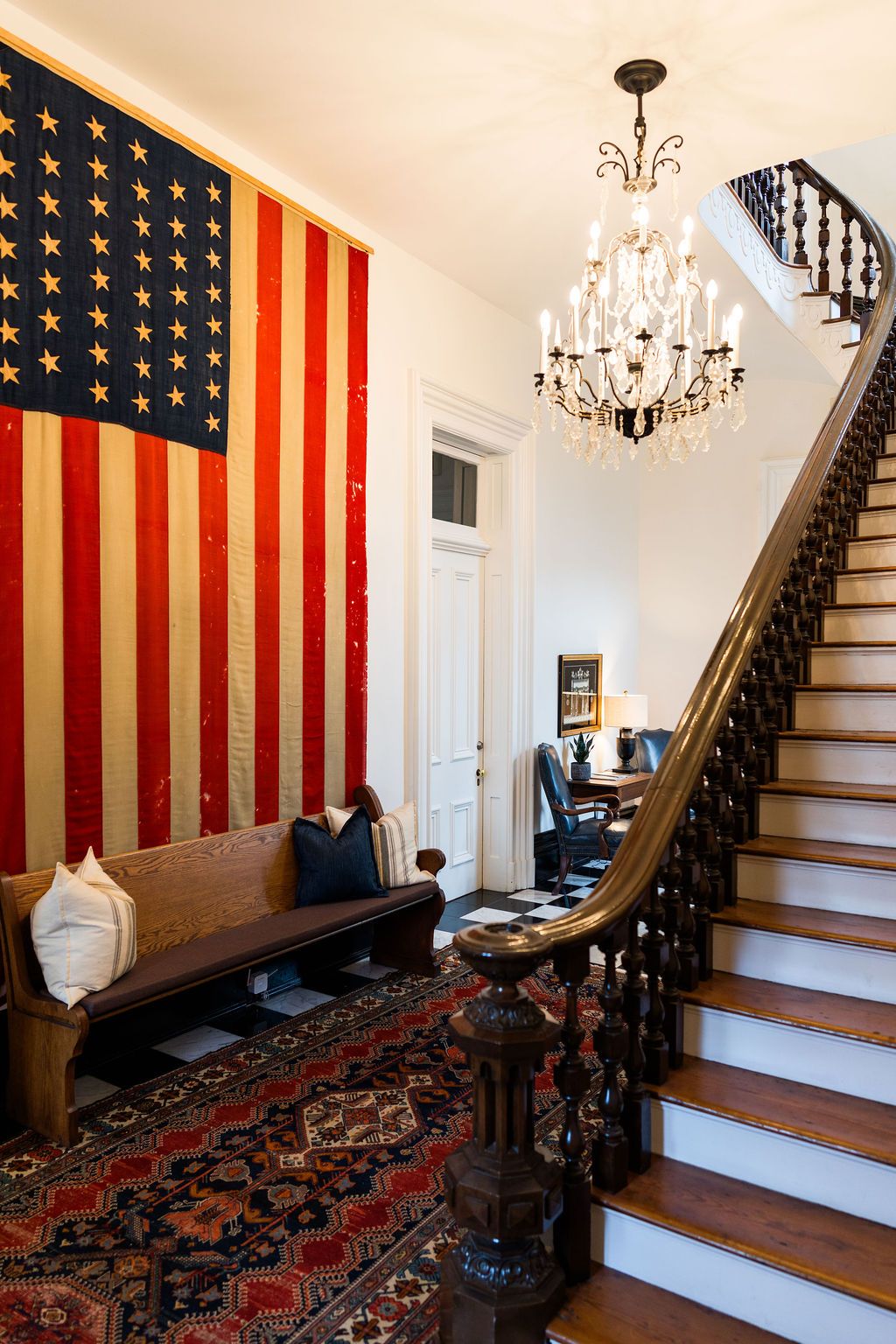Historic American flag, chandelier and carved staircase inside BHA Strategy's Howell House office
