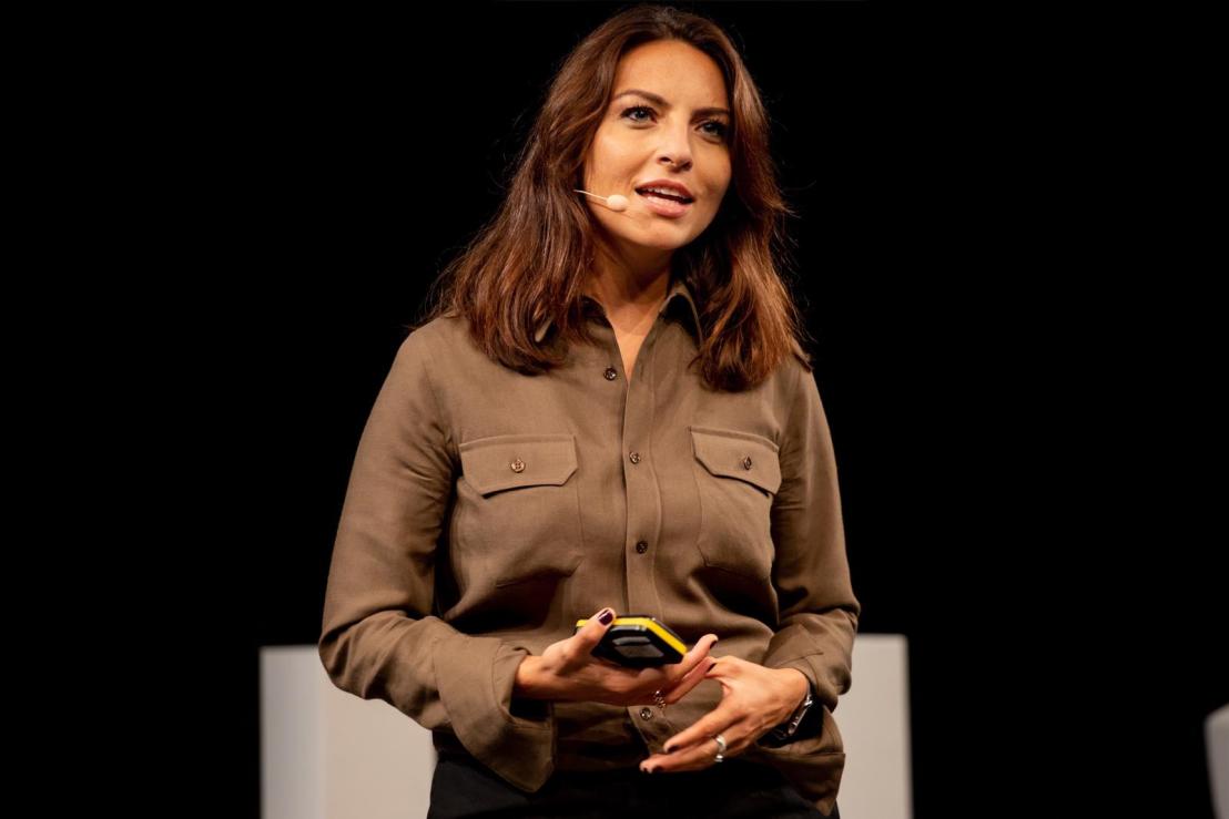 Bianca Anghelina speaking on stage with a headset microphone