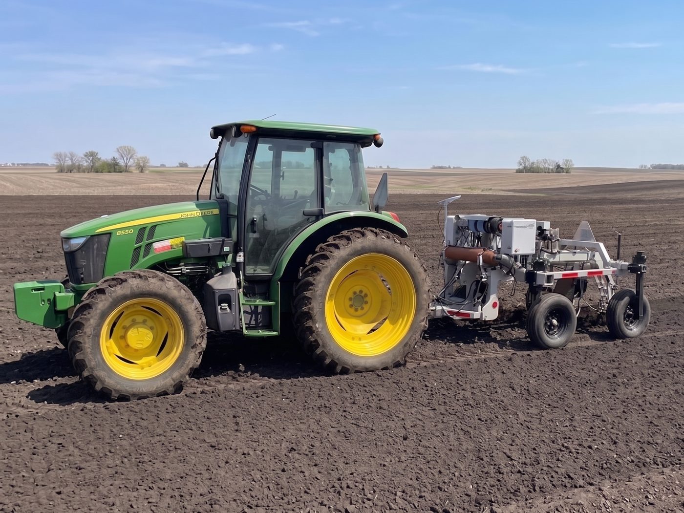 A tractor towing TerraBlaster’s Blaster 1000 soil measurement implement across a field