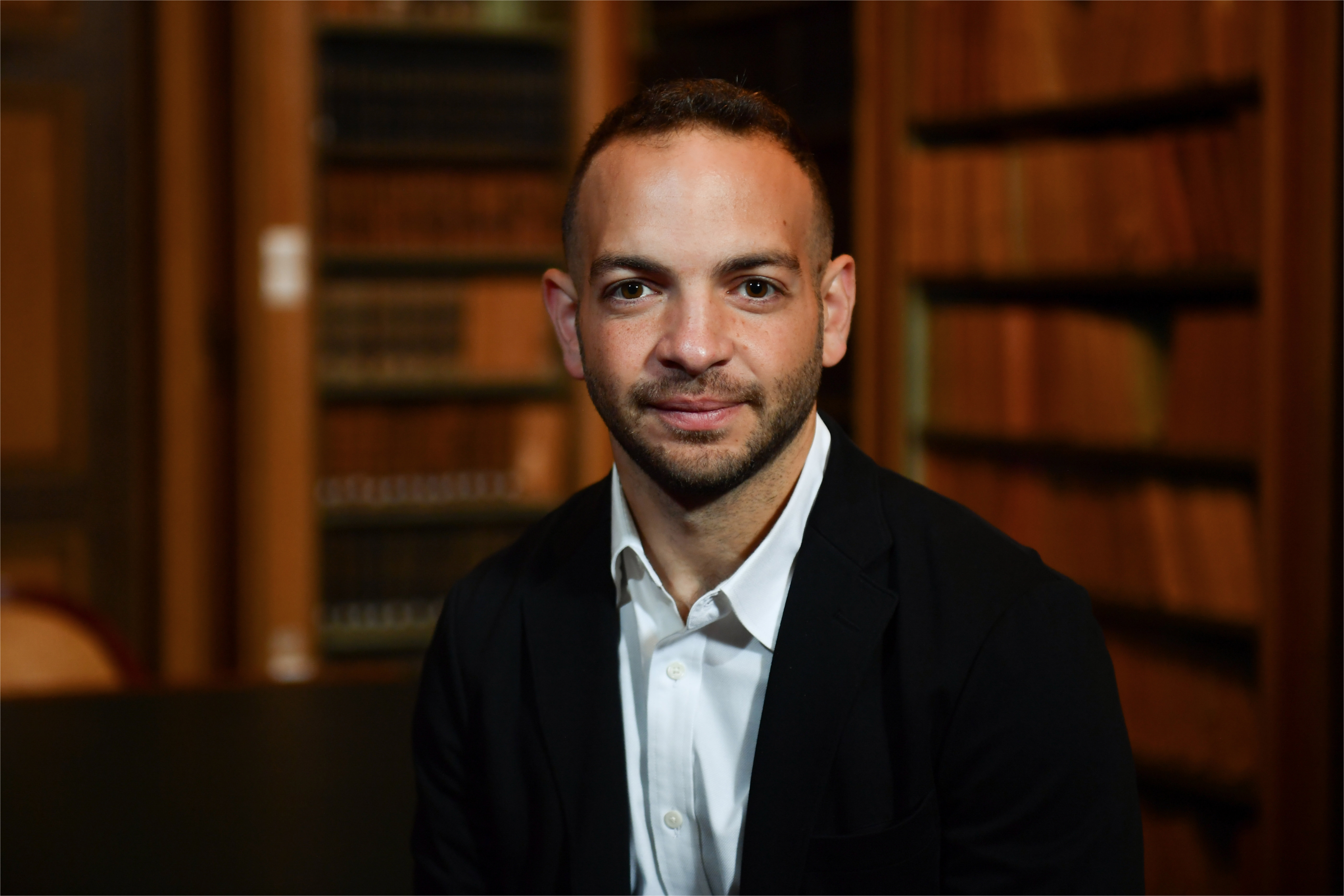 Big Technology founder and host Alex Kantrowitz, photographed in front of bookshelves