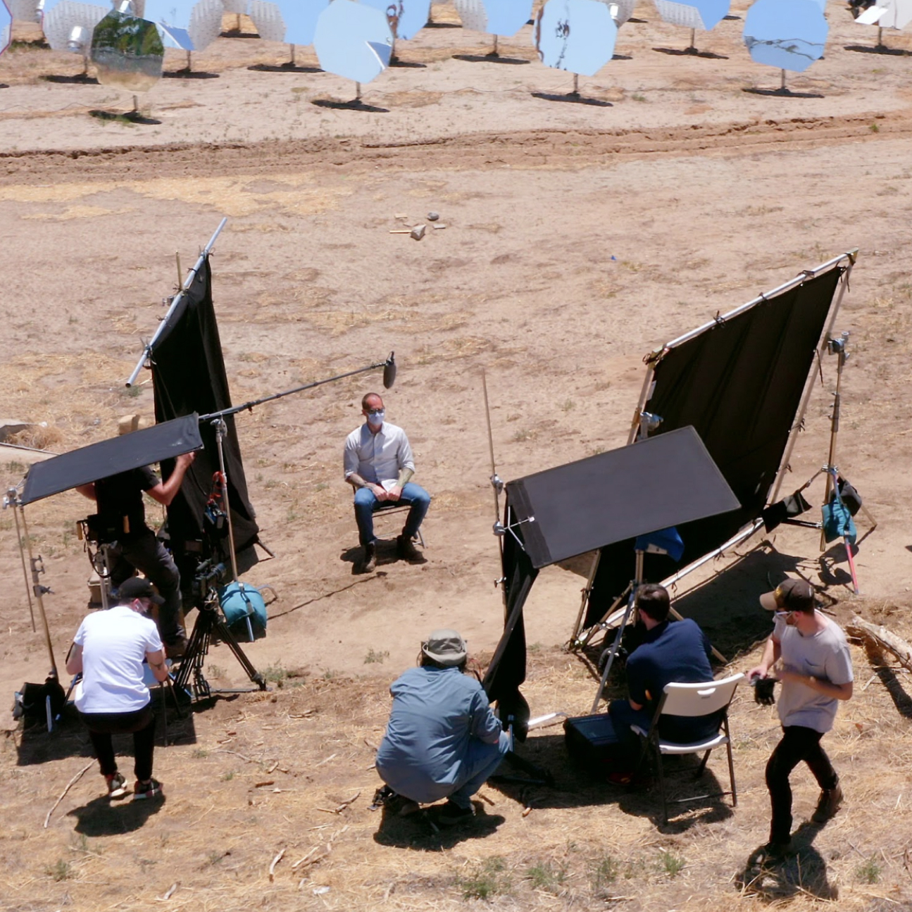 An outdoor interview production with cameras, crew and lighting screens