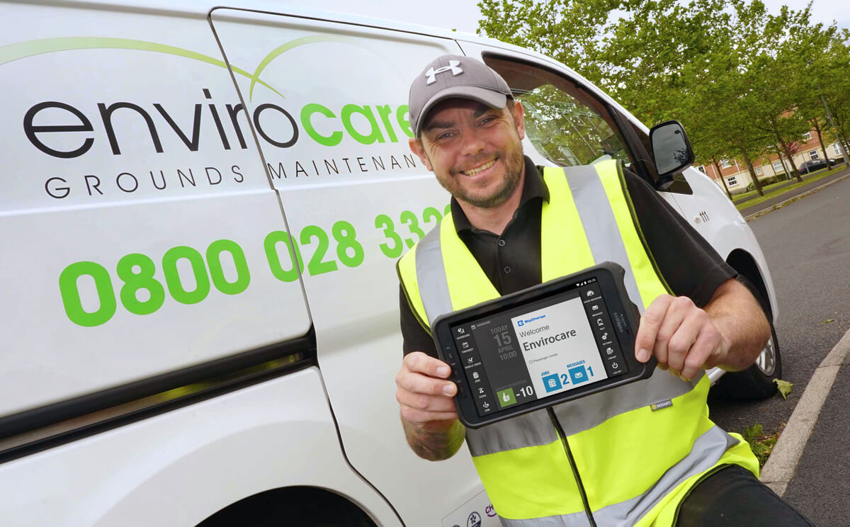 An Envirocare field worker beside a company van holding a tablet running BigChange
