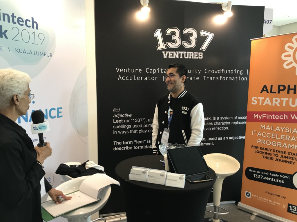 Bikesh Lakhmichand speaking with an interviewer at the 1337 Ventures stand at MyFintech Week 2019