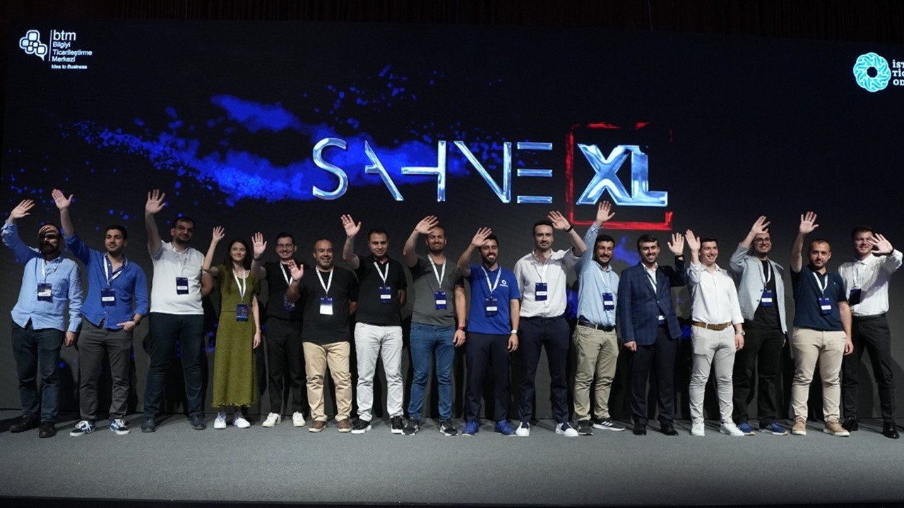 A founder presenting on the blue-lit Sahne XL stage in front of an audience