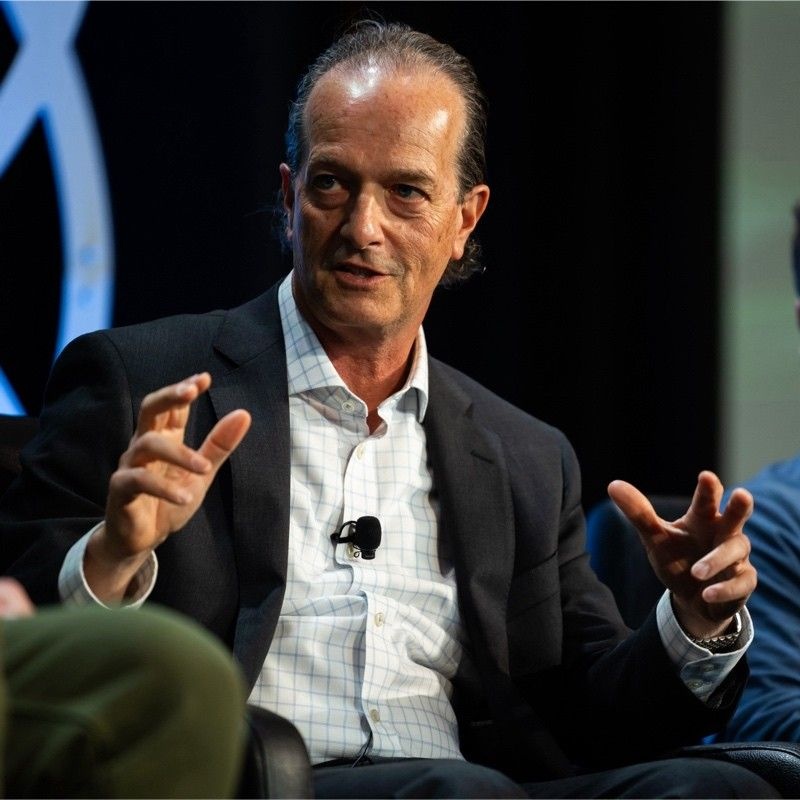 Bill Brady seated with a lapel microphone, gesturing with both hands while speaking