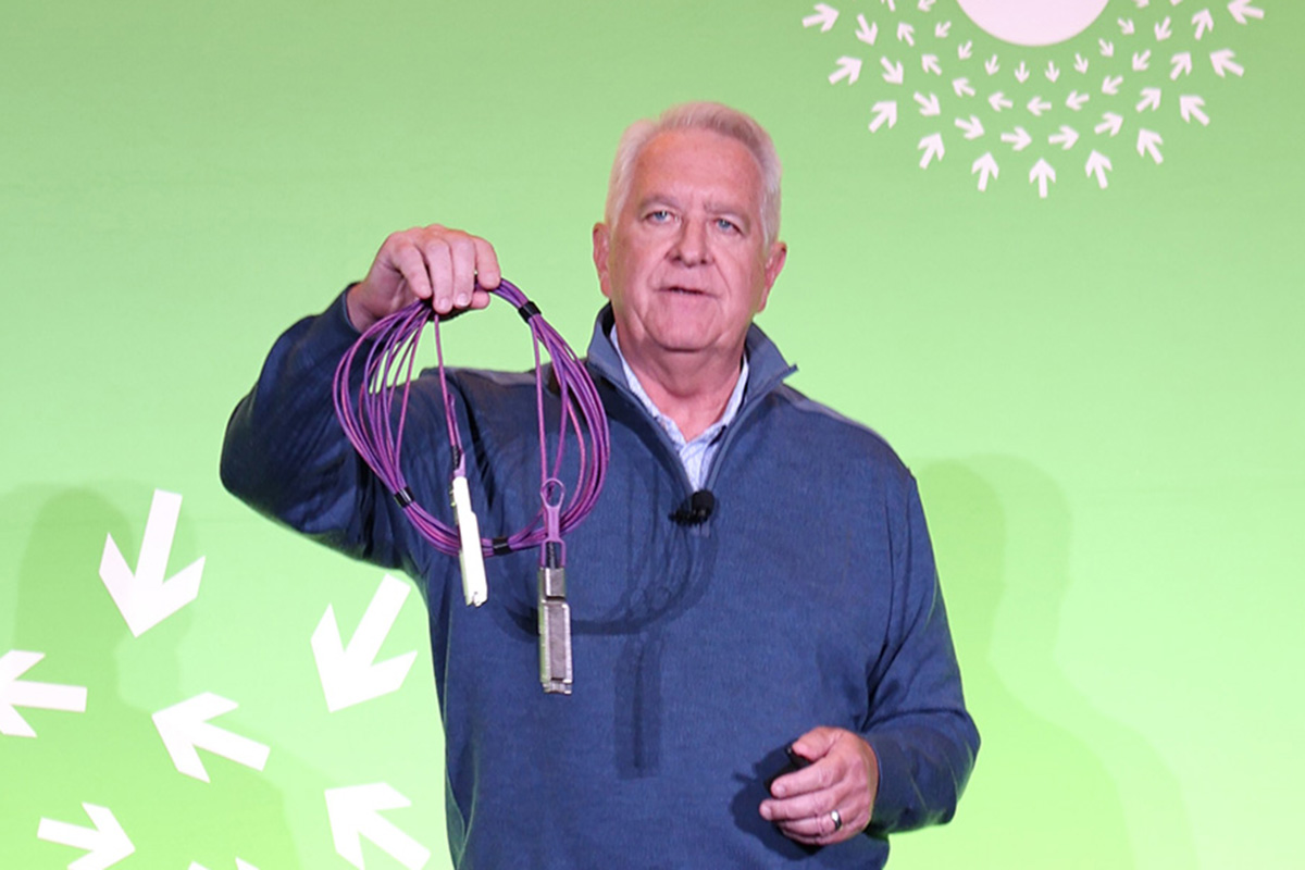 Bill Brennan holds a purple active light cable during his OCP Global Summit 2026 presentation