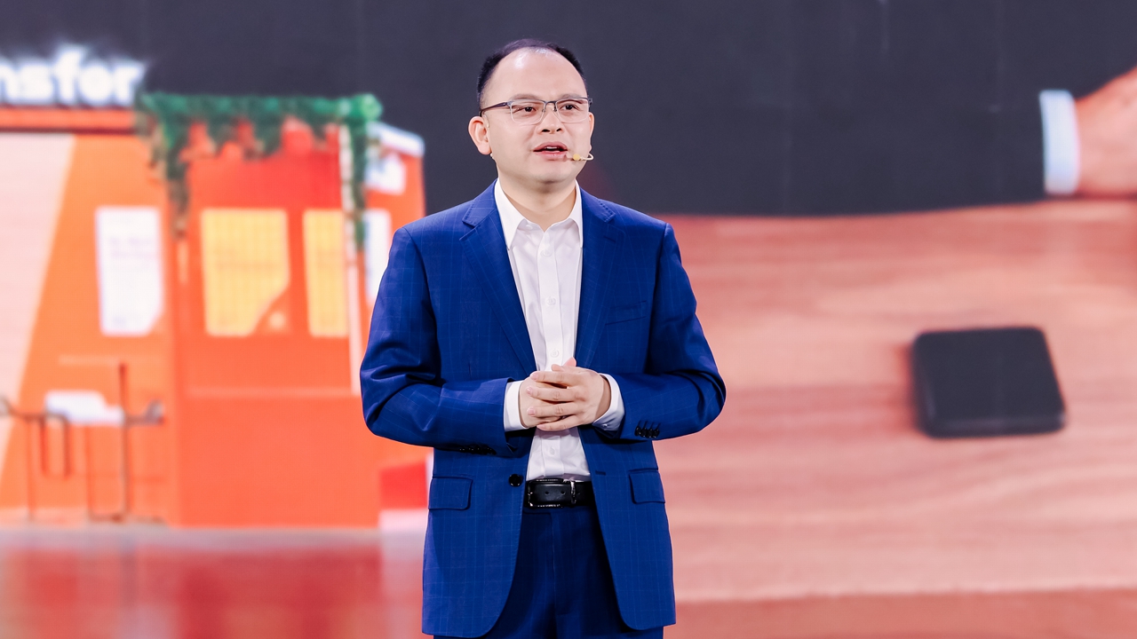 Bill Deng speaking on stage in a blue suit at the XTransfer Summit 2026 in Shenzhen