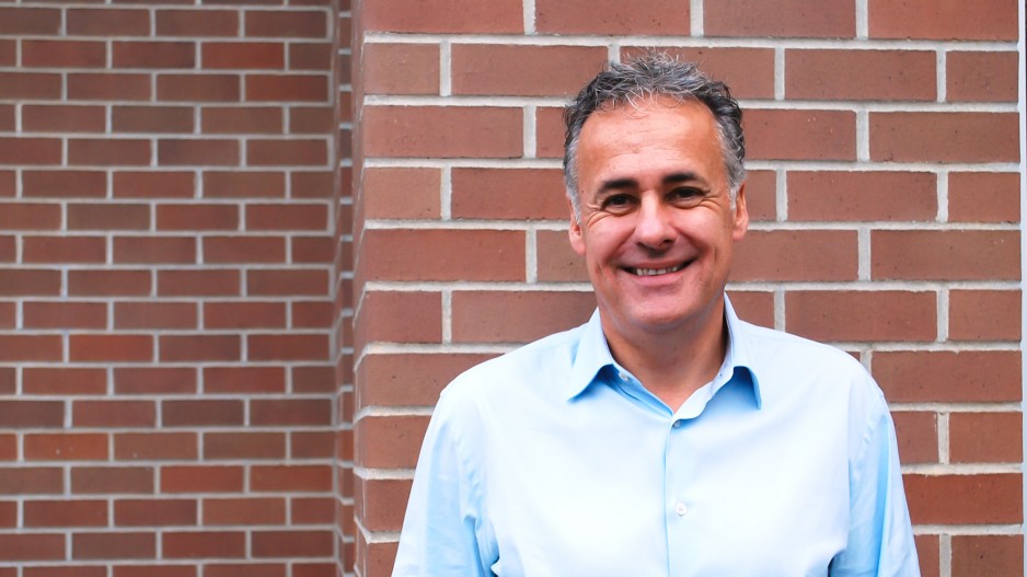 Bill Hunter smiling in a light blue shirt in front of a brick wall