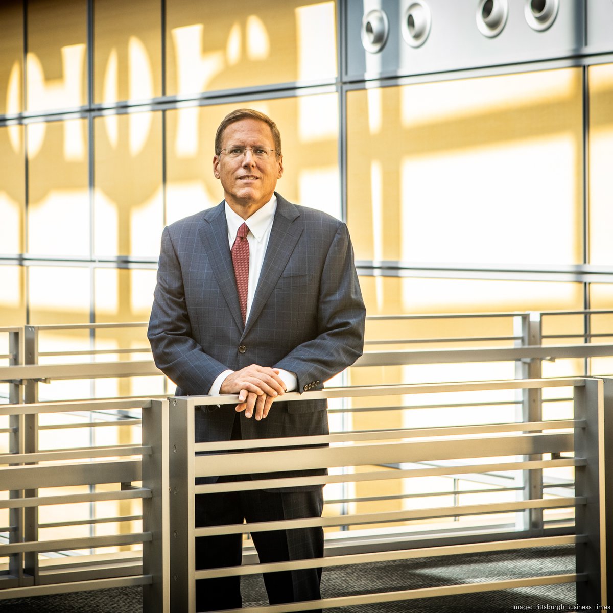Bill Oplinger standing at an interior railing in front of illuminated Alcoa lettering