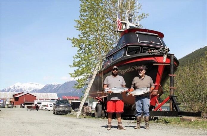 Bill Thomas and his son Cole holding fish in front of their fishing vessel