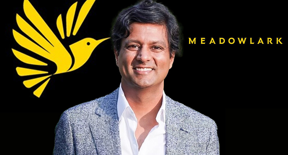 Bimal Kapadia in front of the yellow Meadowlark bird and wordmark