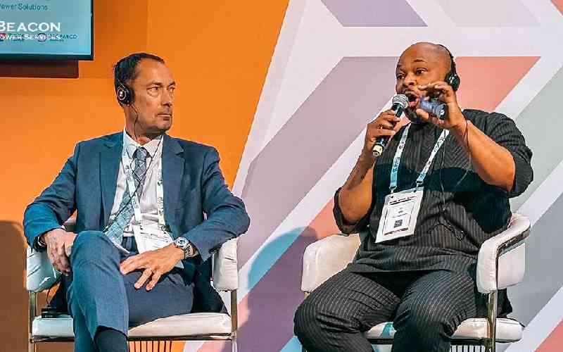Bimbola Adisa, seated at right, speaking into a microphone on a panel at the Africa Forward Summit.