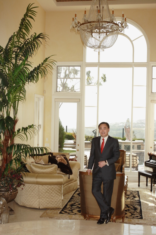 Bing N. Sun standing in his California home beneath a chandelier