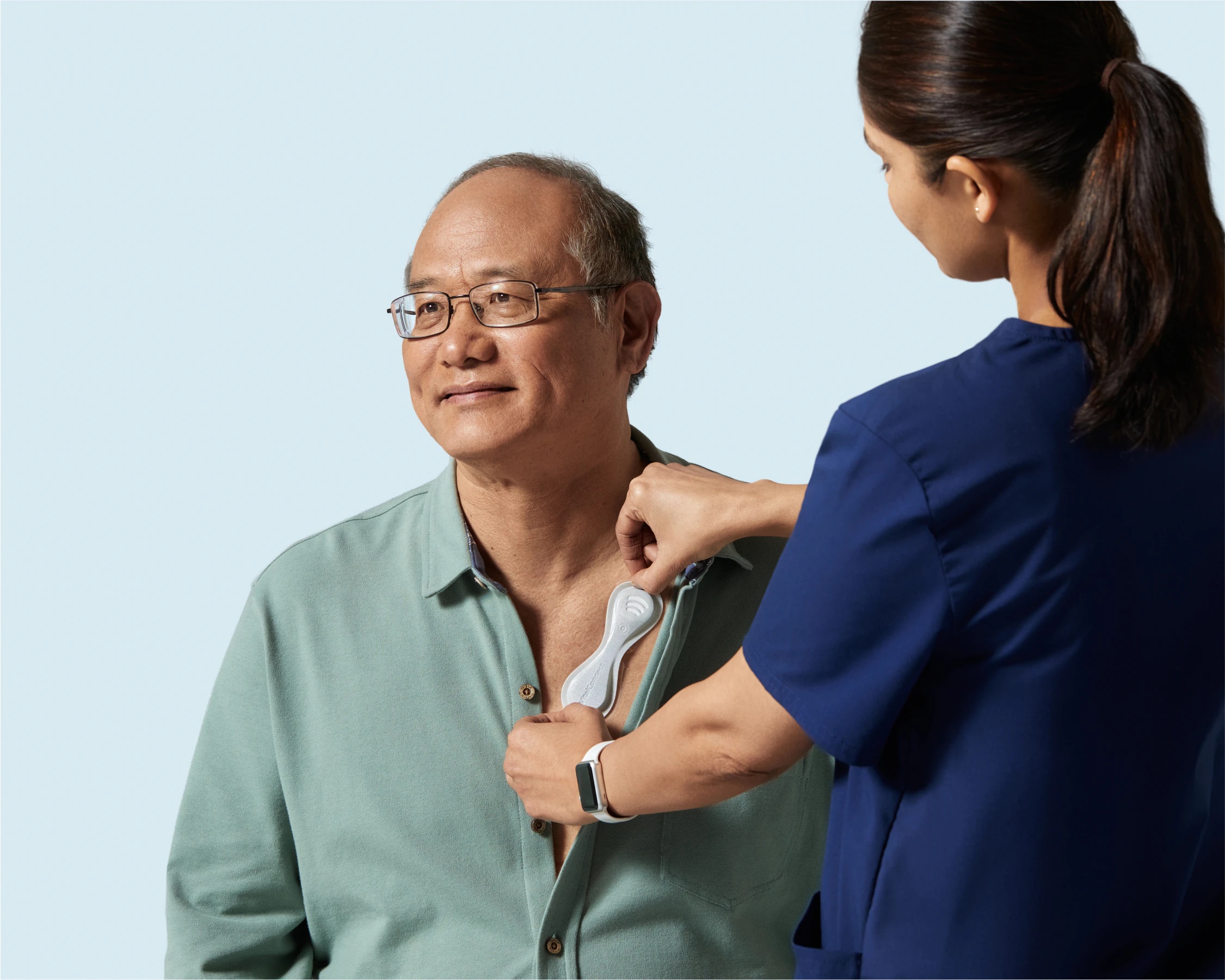 A clinician fits a connected ECG sensor to a man’s chest in a Biofourmis promotional photograph