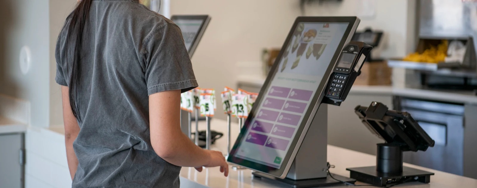 A guest using a self-ordering kiosk at a restaurant counter