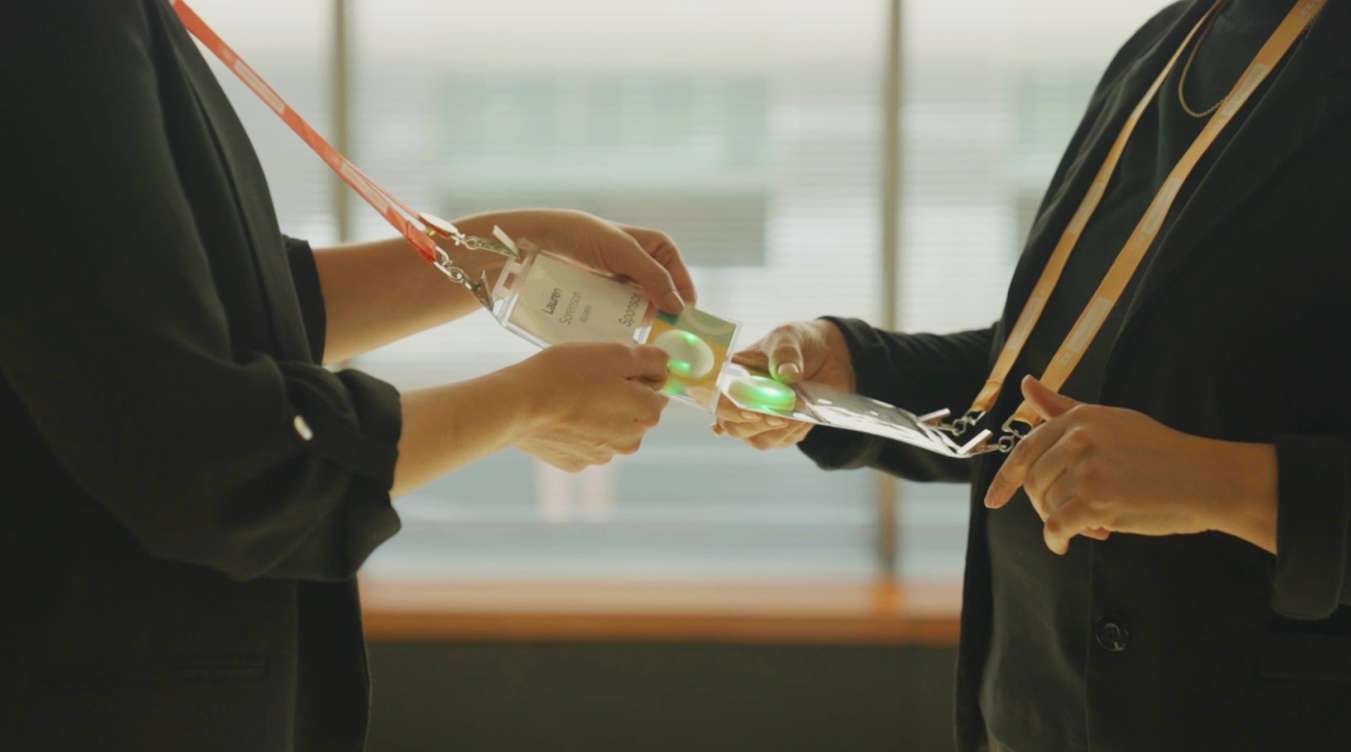 Two event attendees tap illuminated Klik SmartBadges together