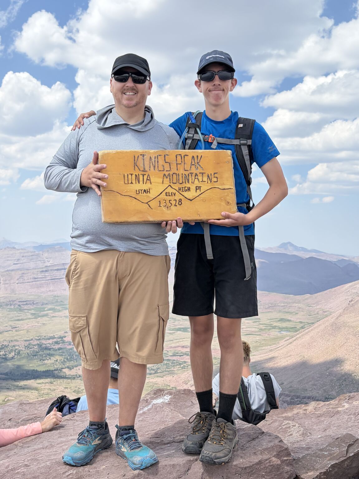 BJ Dodenbier and his son holding the Kings Peak summit sign at 13,528 feet in Utah