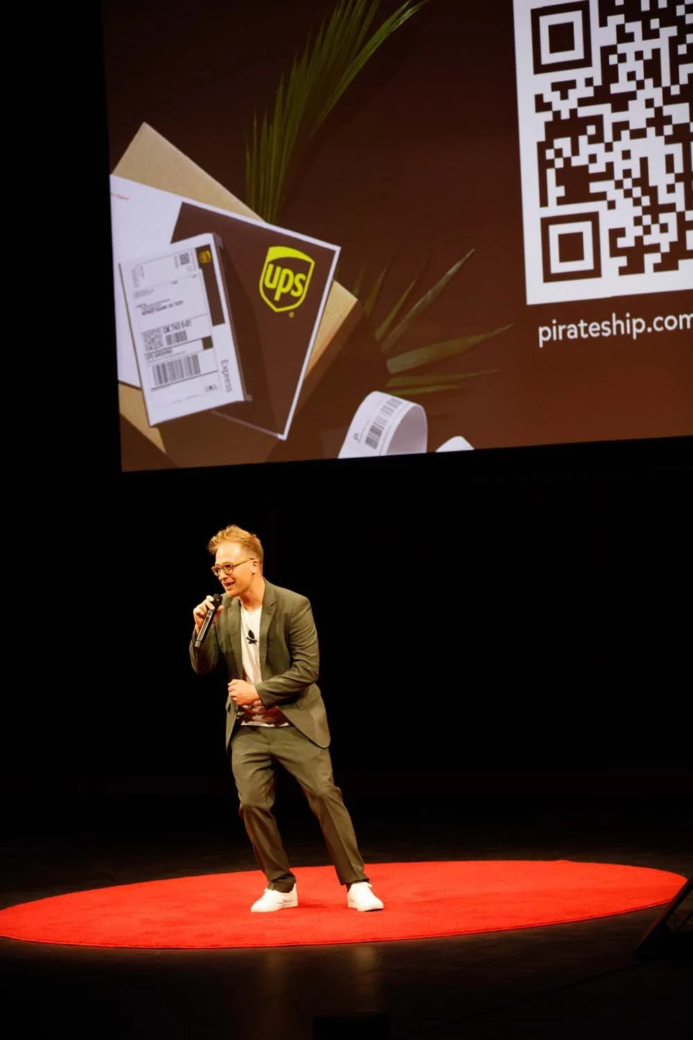 Bjorn Borstelmann speaking on a stage with a Pirate Ship shipping label projected behind him