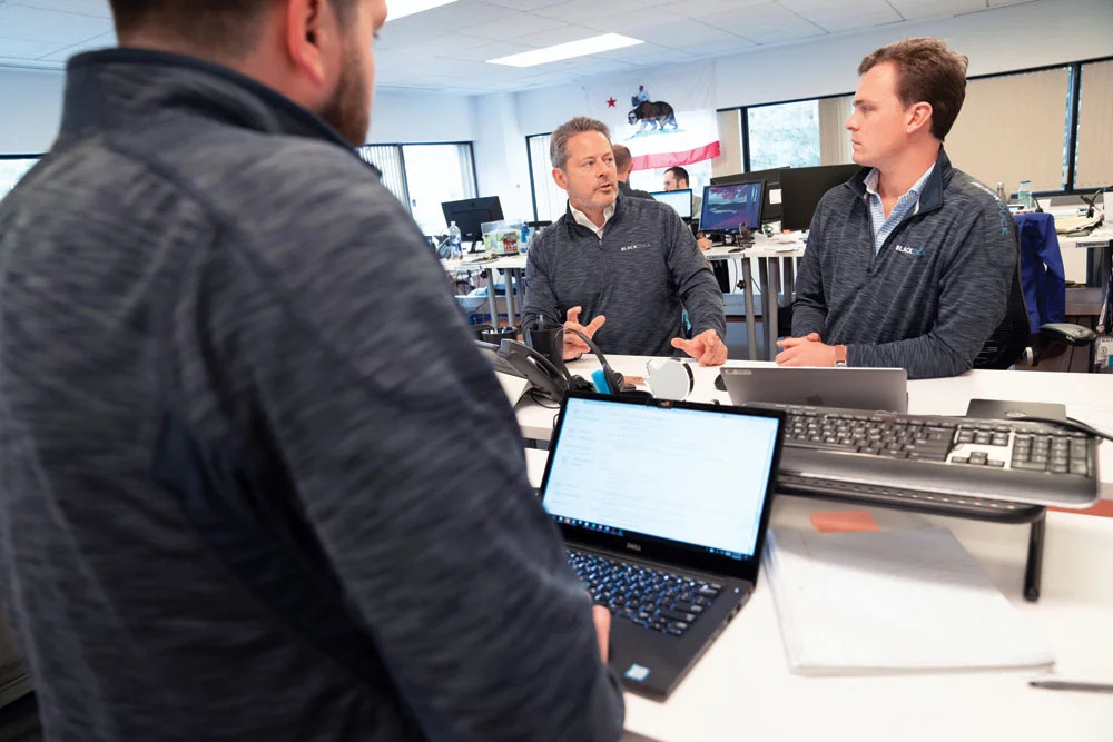 Three Black Duck team members collaborating at a desk in an office