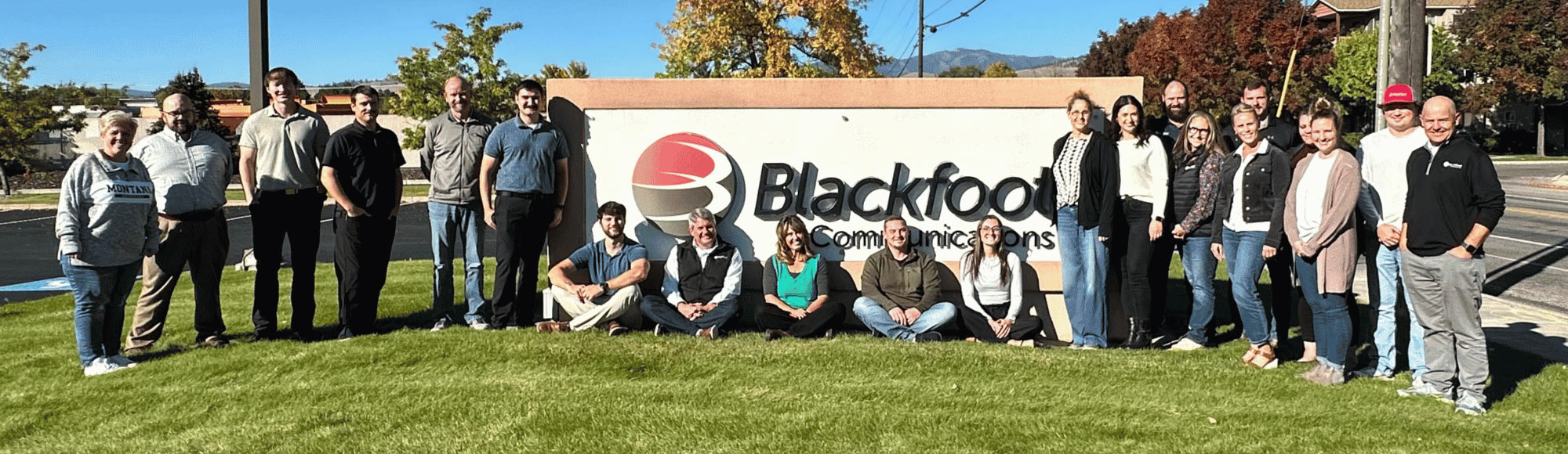 Blackfoot team members gathered outdoors beside the company sign