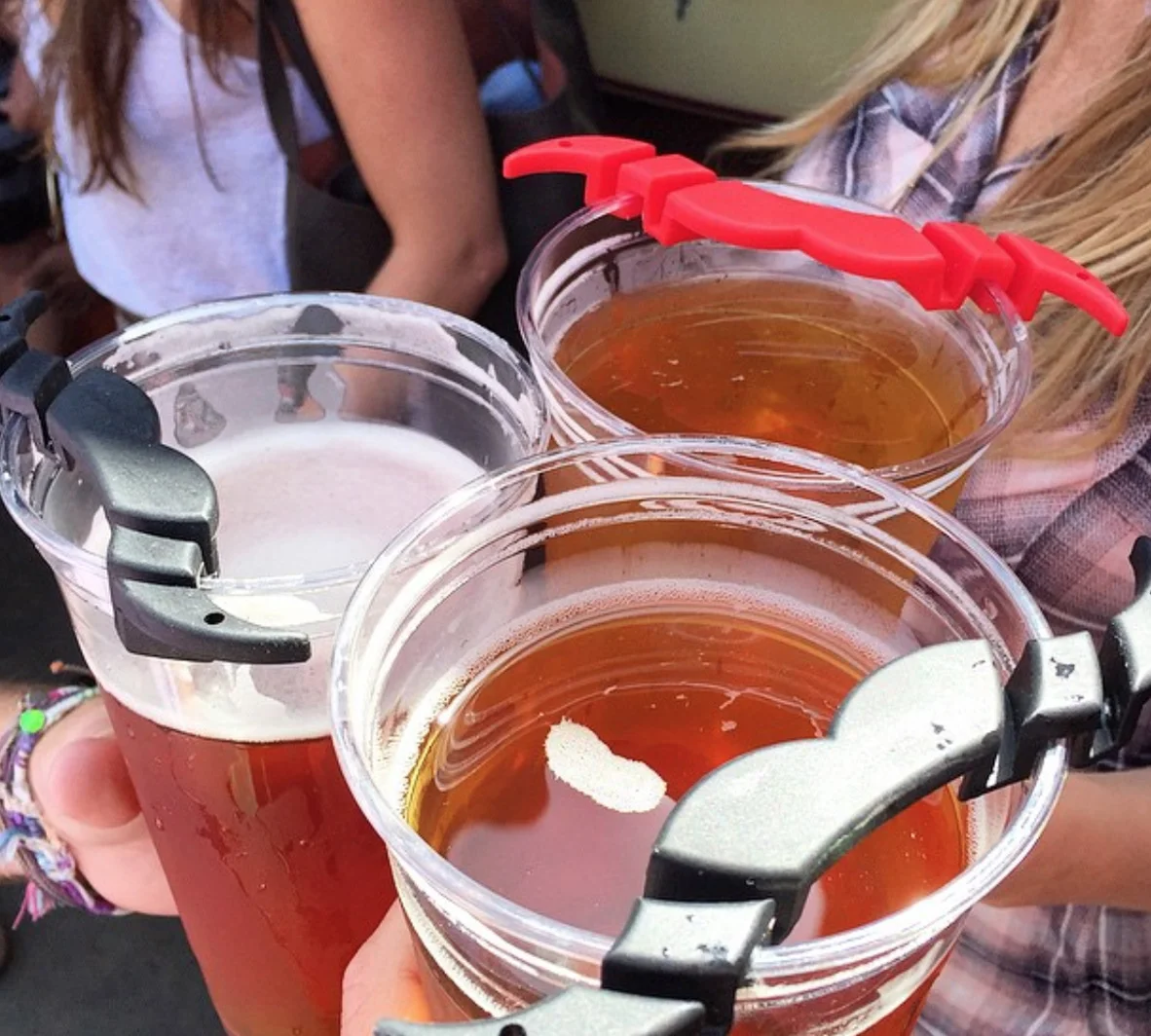 Red and black MoGuard attachments resting across three drinking cups