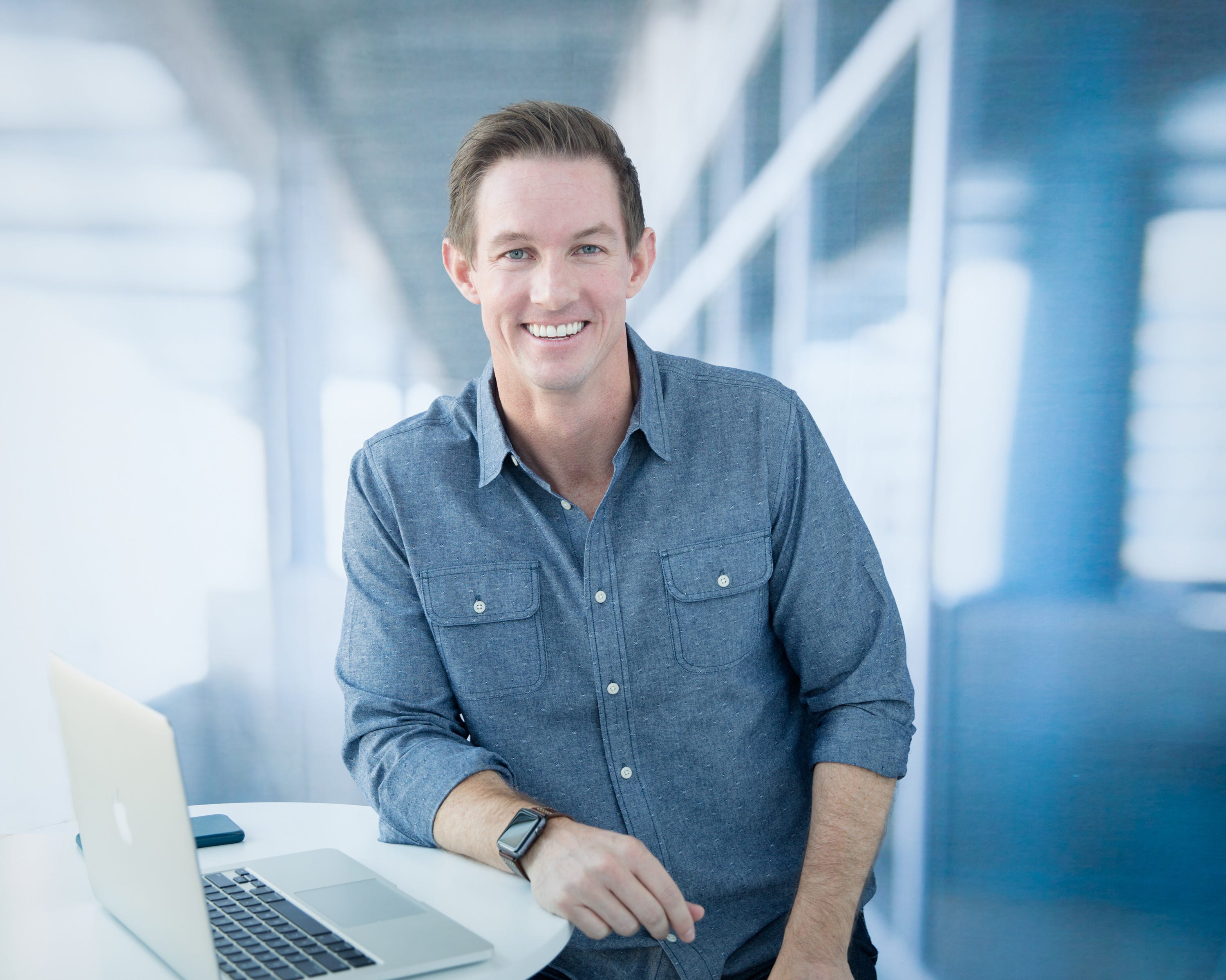 Blake Garrett smiling beside a laptop in a bright office