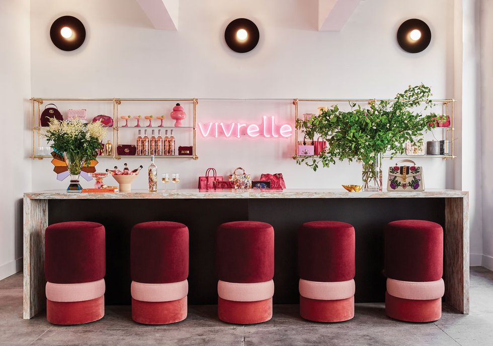 Vivrelle’s New York showroom bar, with burgundy stools, flowers and accessories displayed behind it