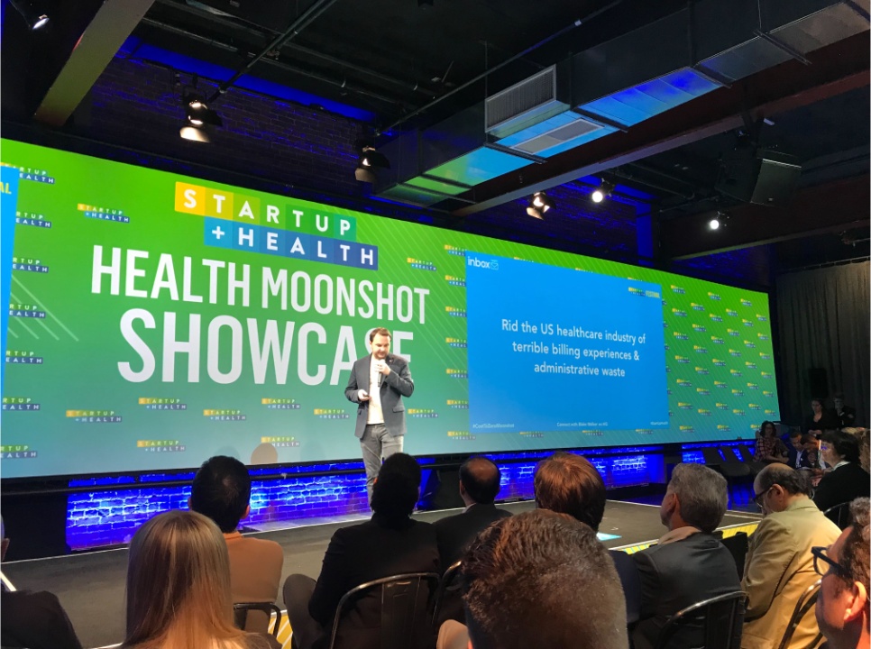 Blake Walker holding a microphone while presenting Inbox Health on a conference stage