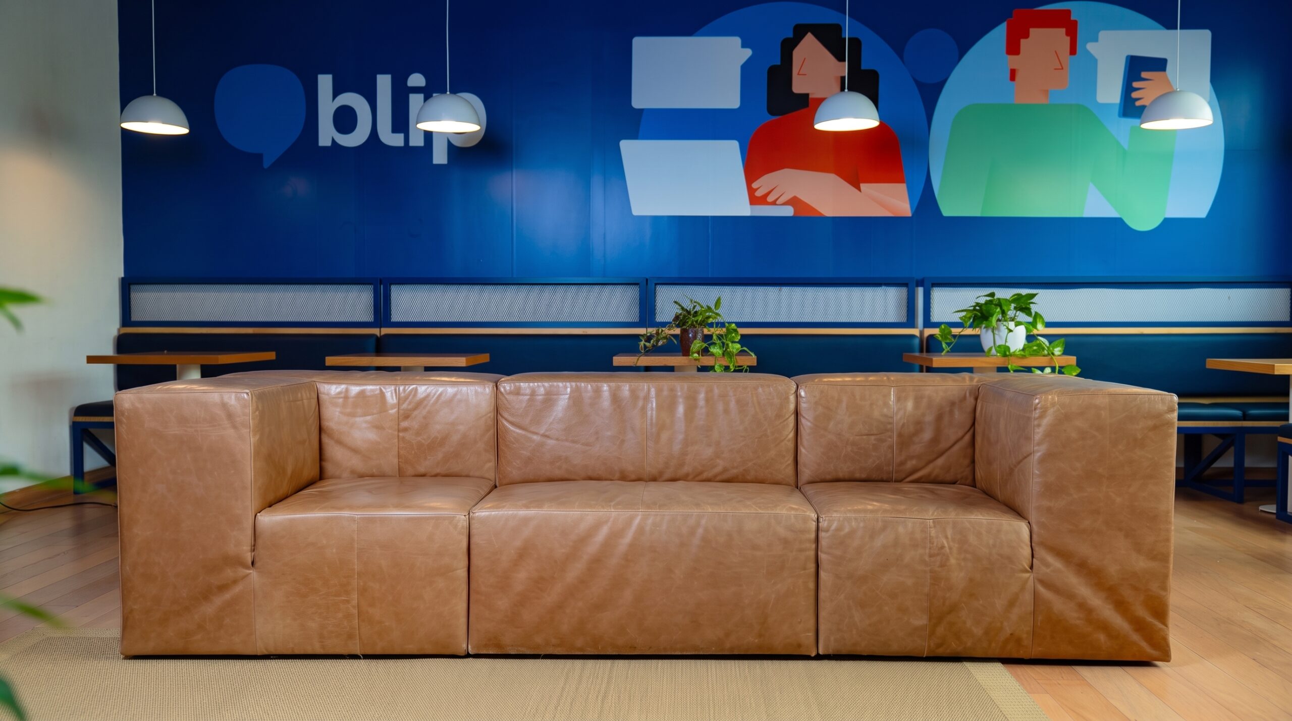 Blip’s Belo Horizonte office lounge, with a leather sofa and illustrated wall
