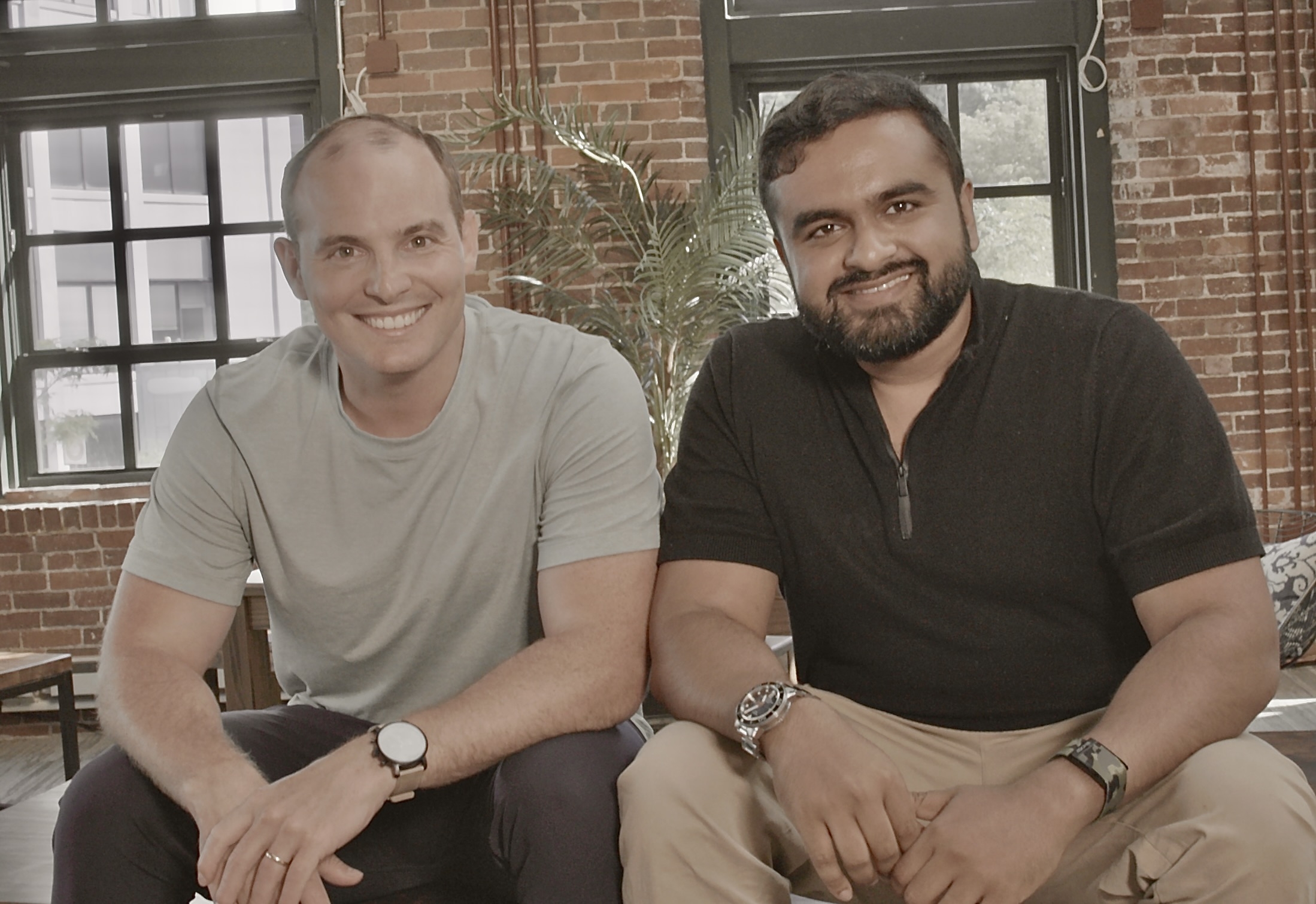 Blitzy co-founders Brian Elliott, left, and Sid Pardeshi, right, seated together in a brick-walled room