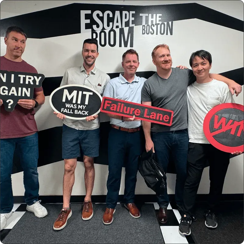 Multitude Insights team posing with playful signs at Escape the Room Boston