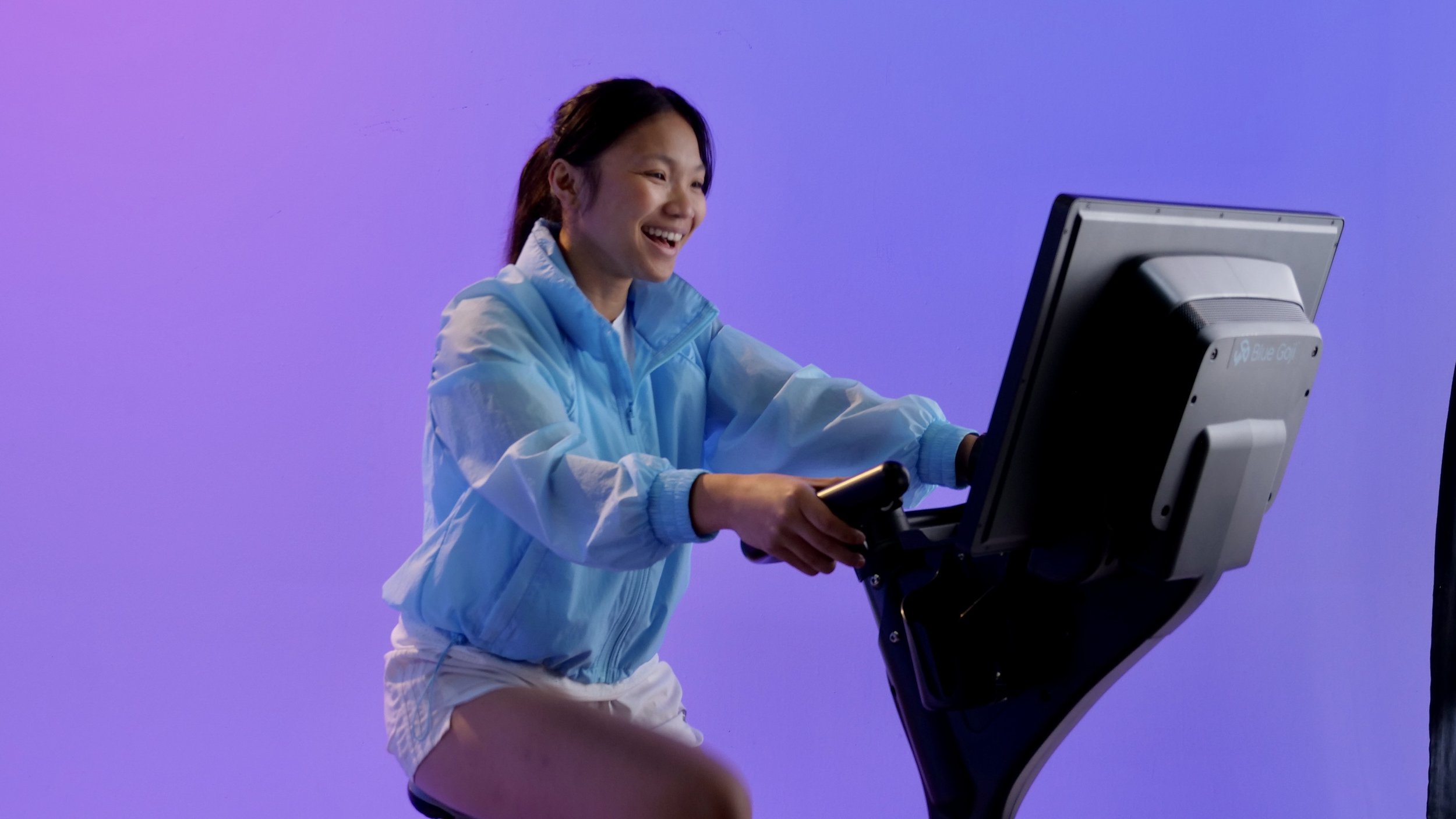 A rider smiling while using Blue Goji gaming handlebars at an exercise-bike demonstration