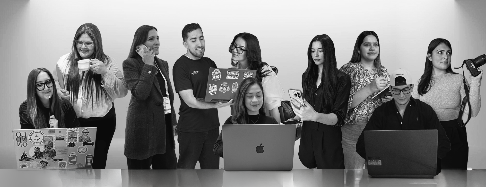 Blue Halo Agency team members gathered around laptops, phones, cameras, and coffee