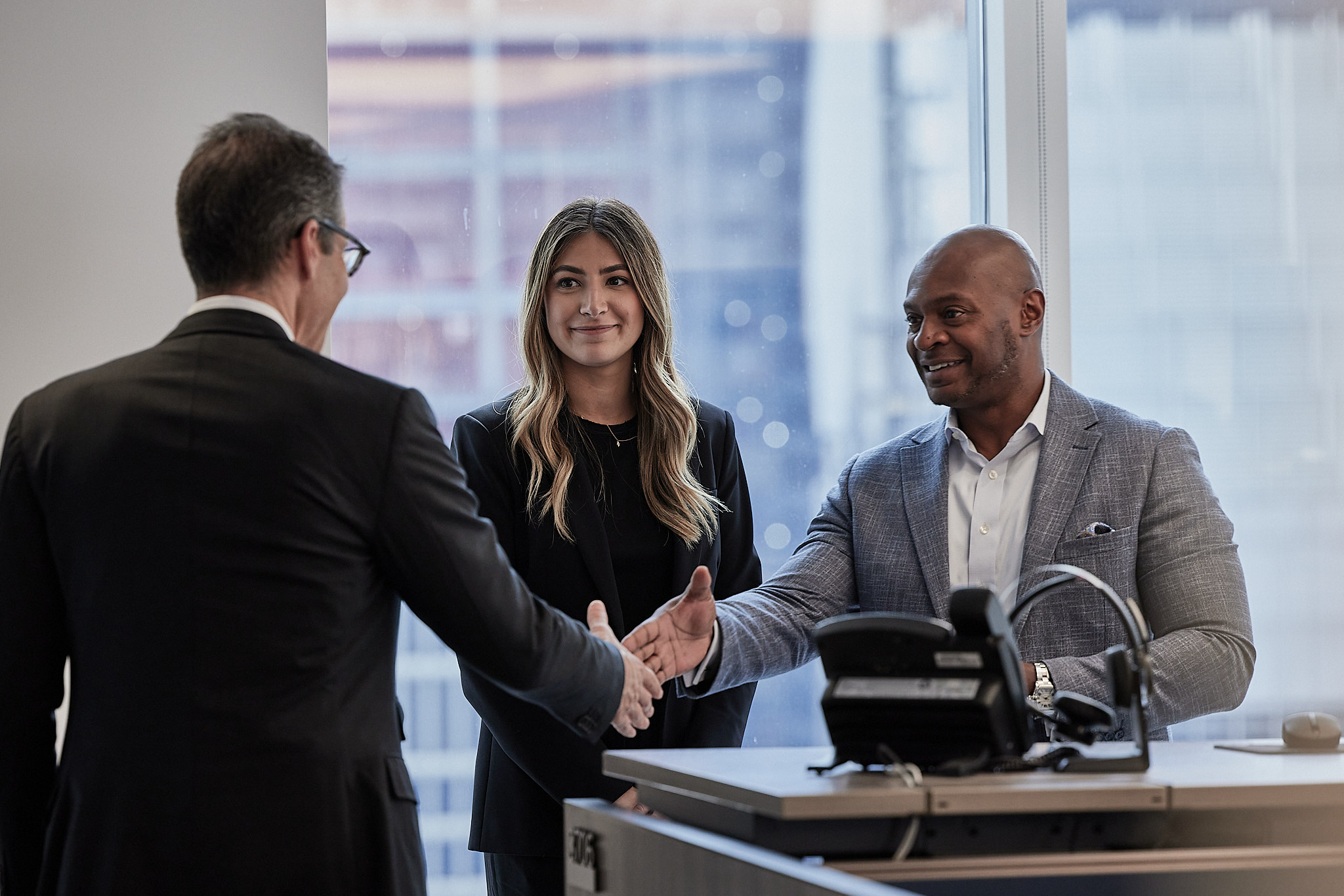 Three people meeting and shaking hands in an office, in Blue Owl’s published culture photography