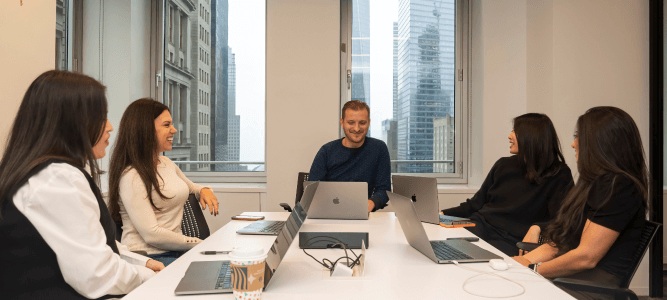Five people meeting around laptops at a Bluecore office
