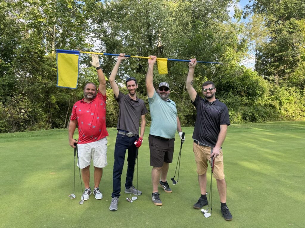 Four people on a golf course in a photograph from Bluewater's company team page