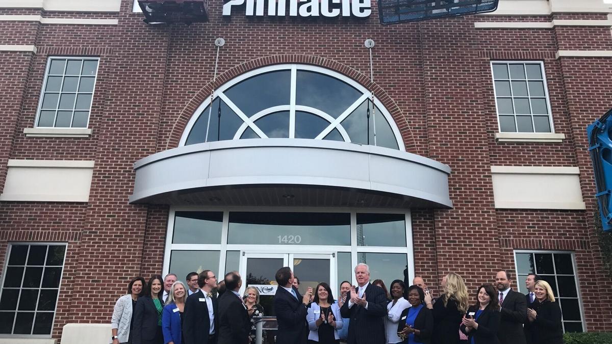 Bank employees and community leaders gather outside a brick branch beneath newly installed Pinnacle lettering in September 2017
