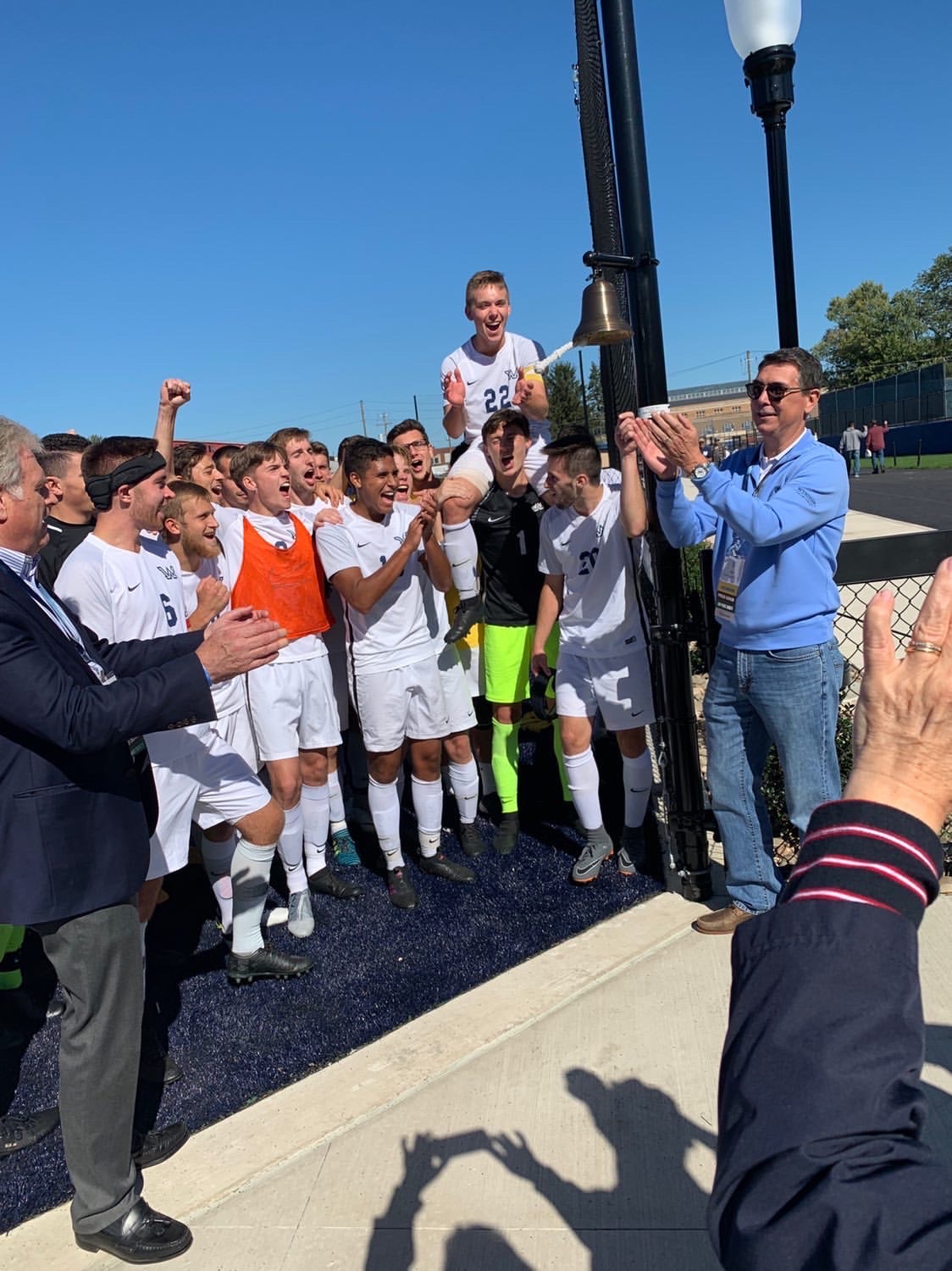 Bob Bruggeworth applauds beside the Wilkes soccer team as a player rings the victory bell