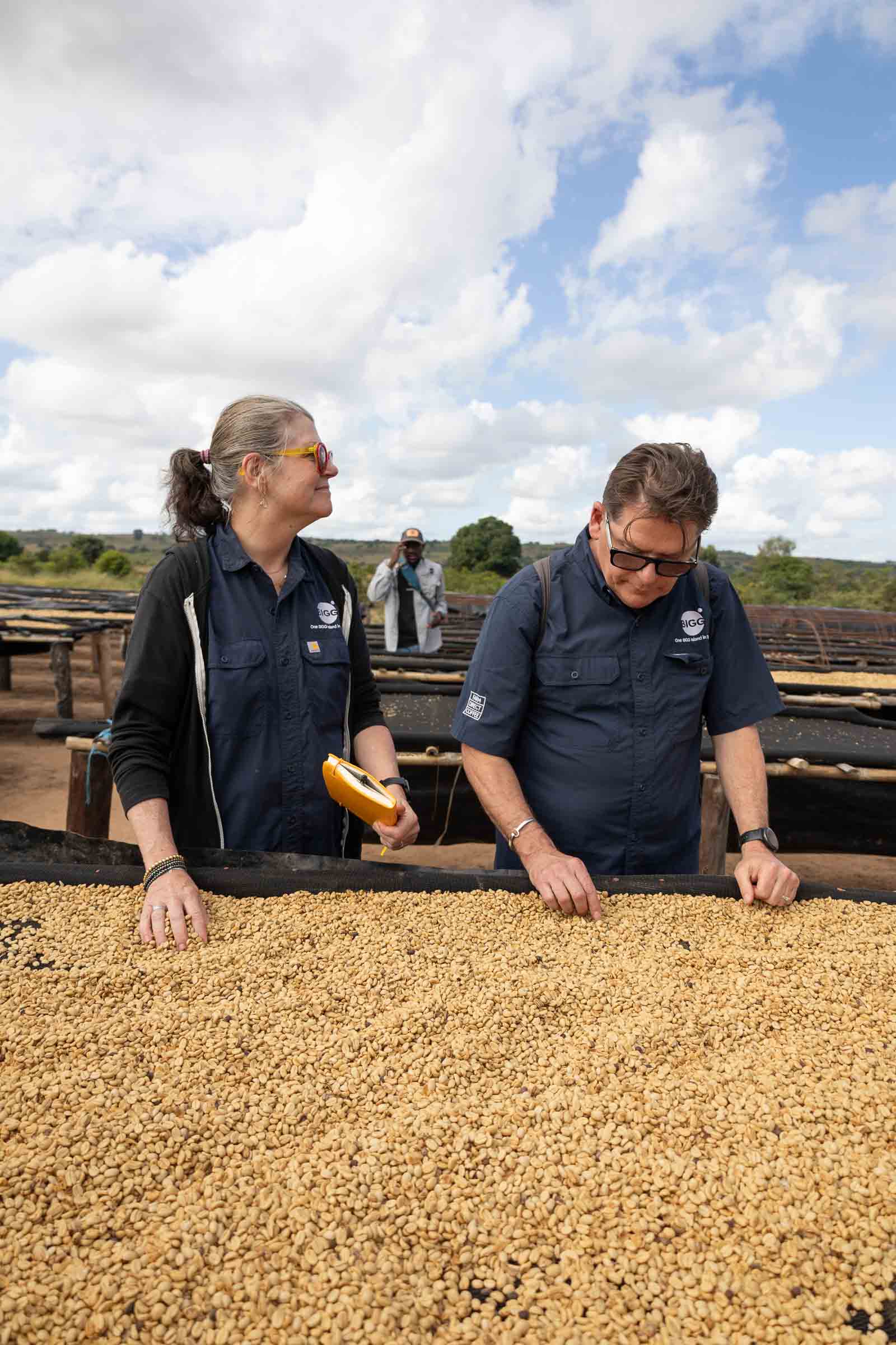 Michelle and Bob Fish inspecting coffee spread across raised drying beds