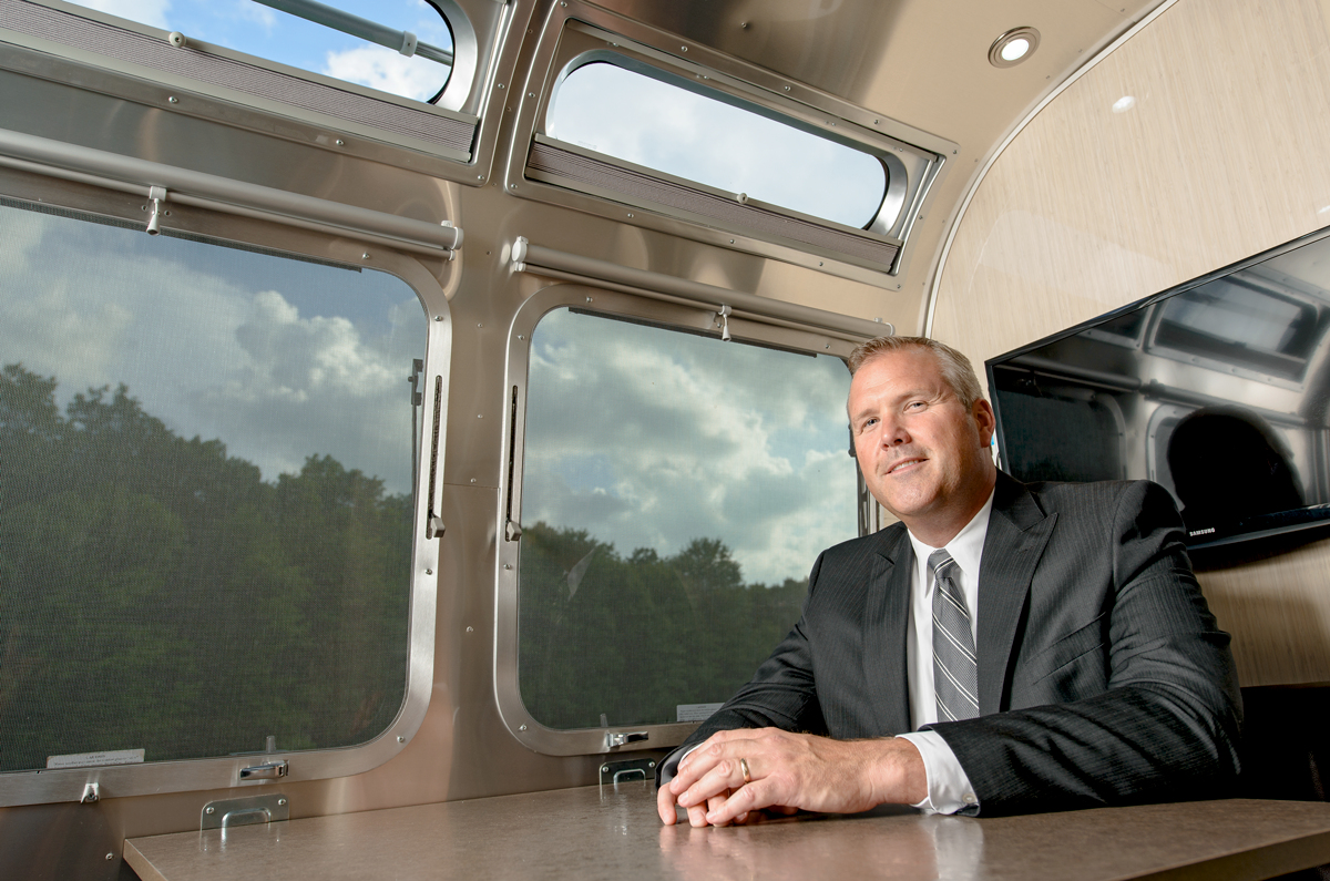 Bob Martin seated at a table inside an Airstream, with curved windows behind him