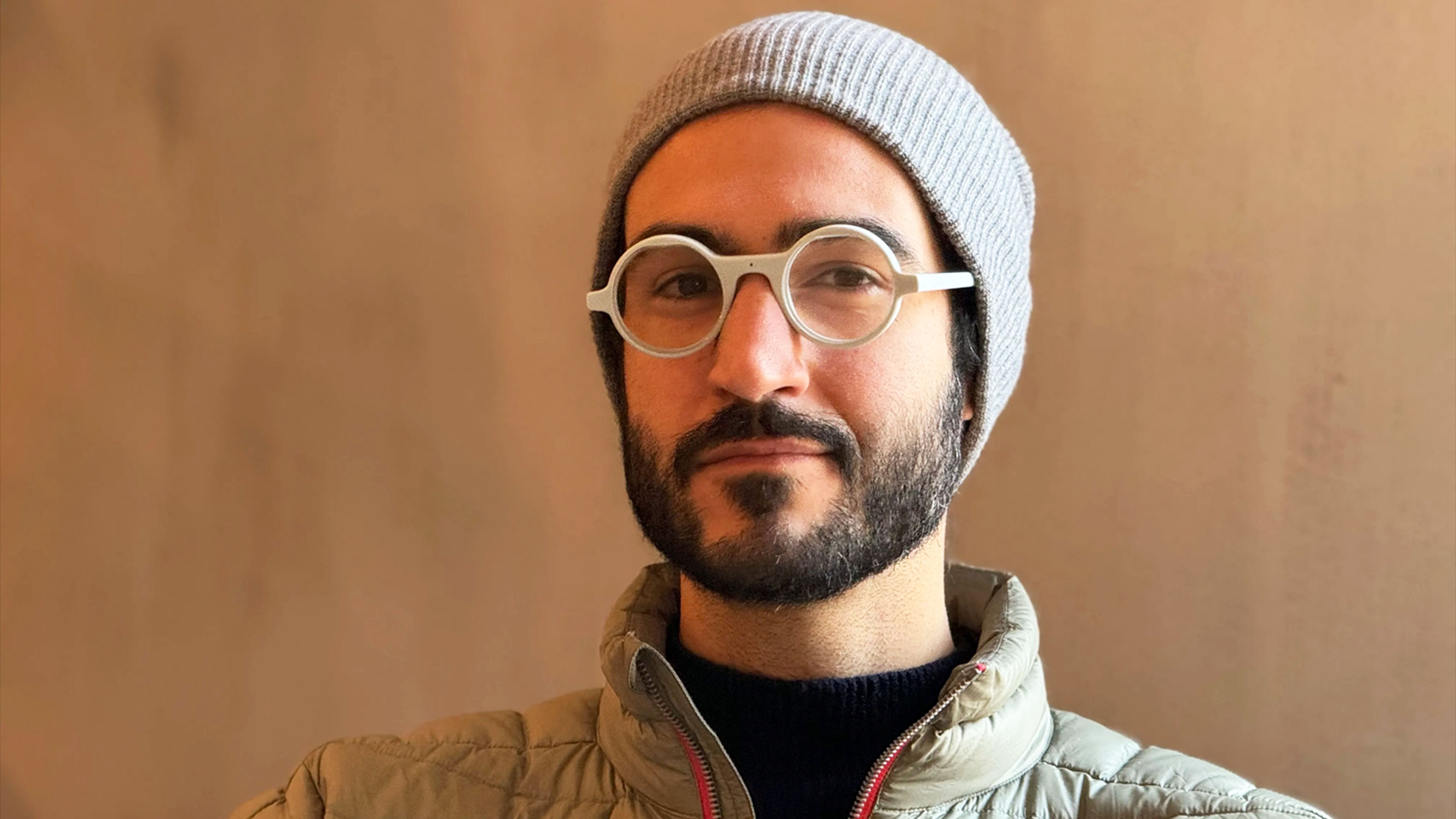 Bobak Tavangar wearing round white Frame smart glasses and a gray beanie