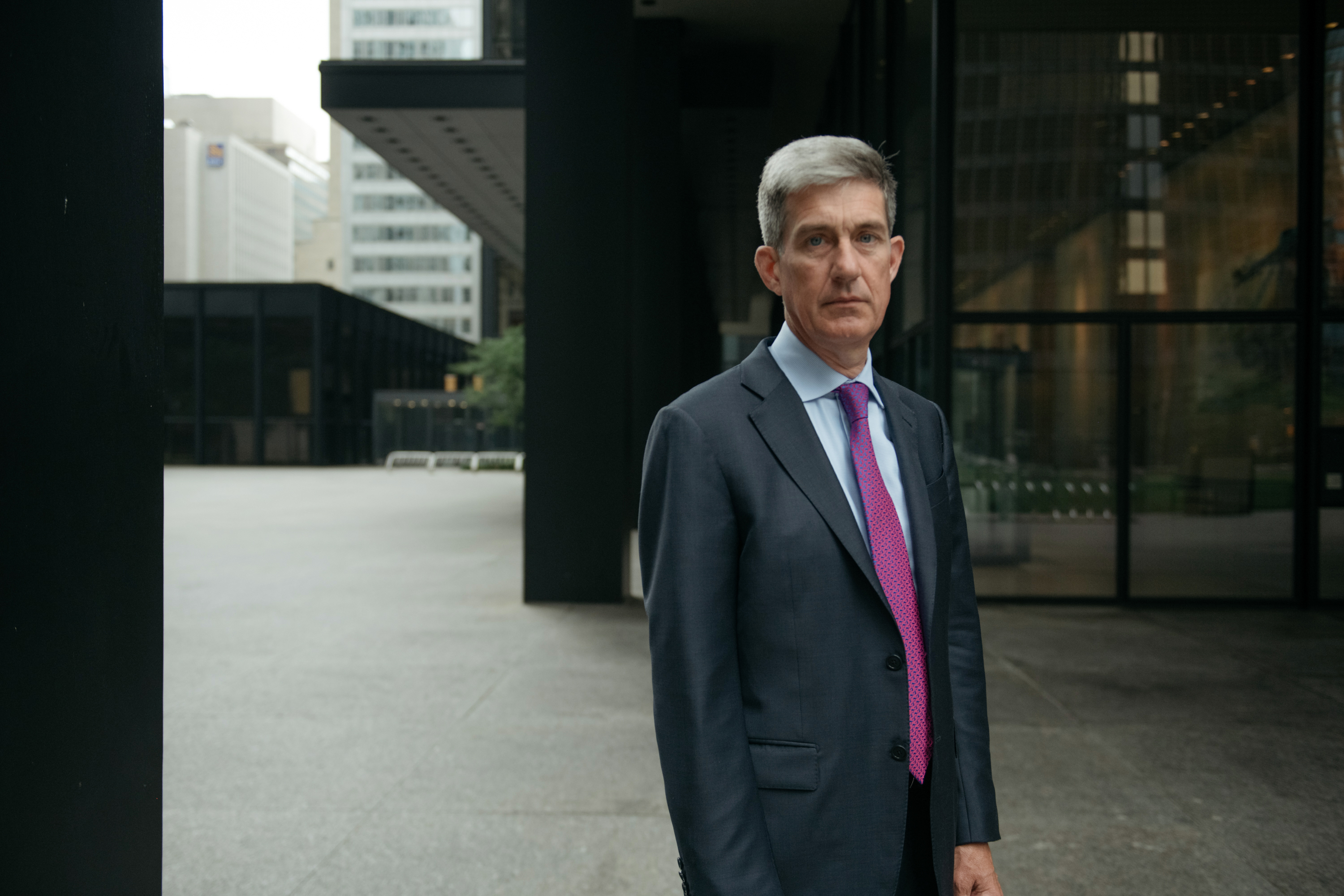 Bobby Le Blanc in a suit, standing outside among glass office buildings