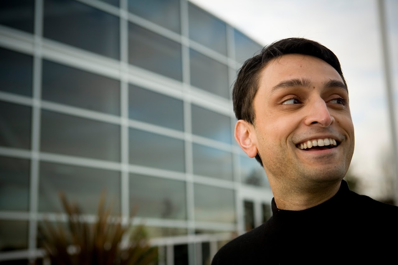 Bobby Mukherjee smiling outside a modern glass building in an early Loka photograph