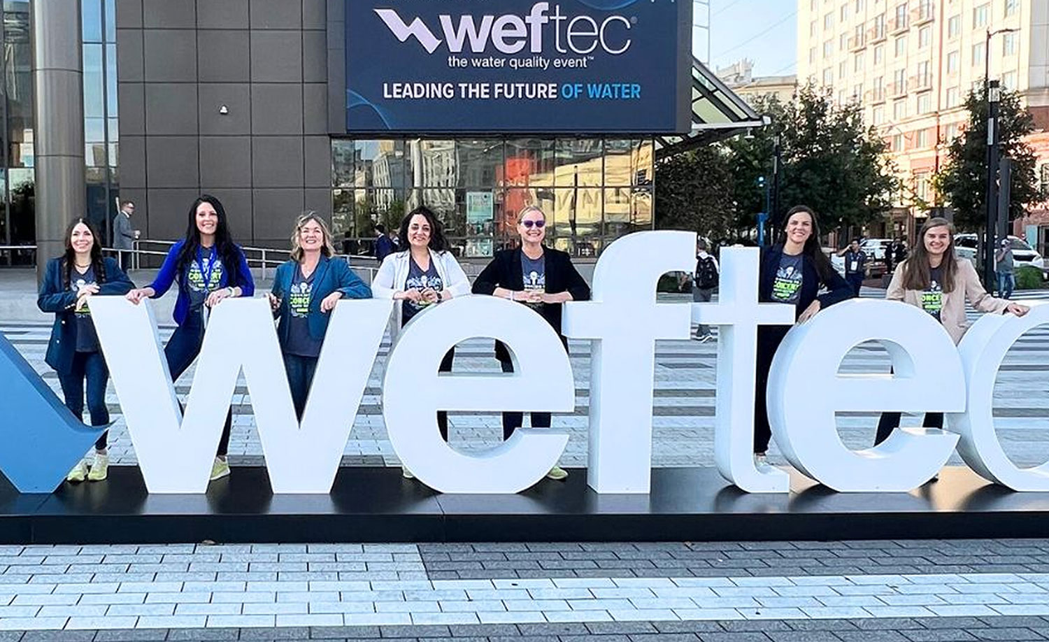 Members of the Boeh Agency team standing behind large WEFTEC letters outside the water industry conference