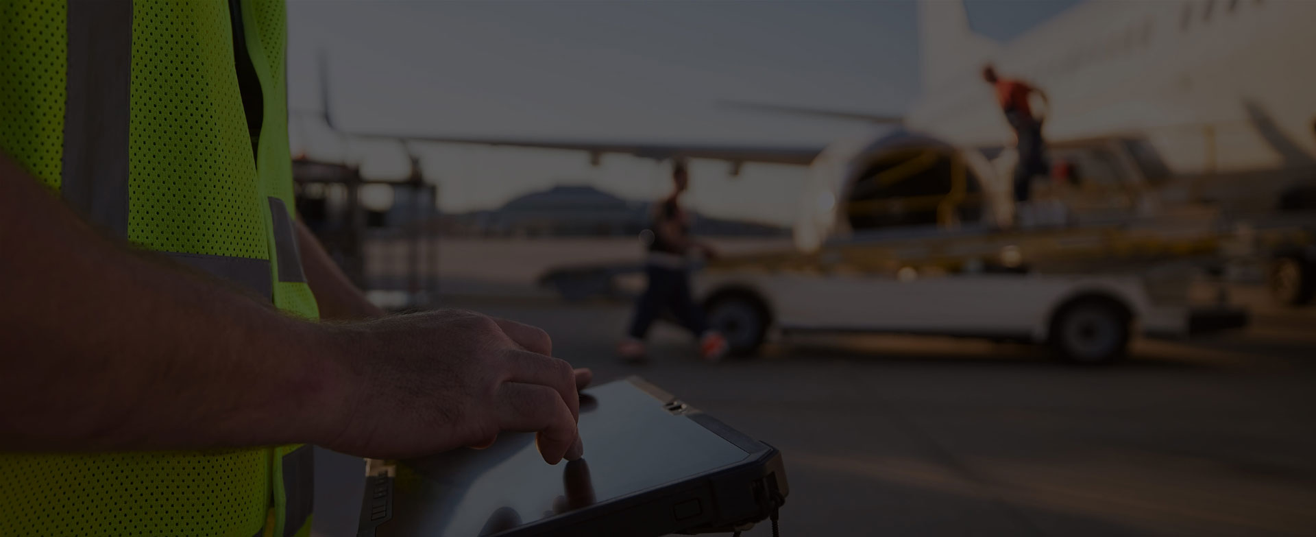 A wireless field engineer works with a rugged tablet beside an airport aircraft