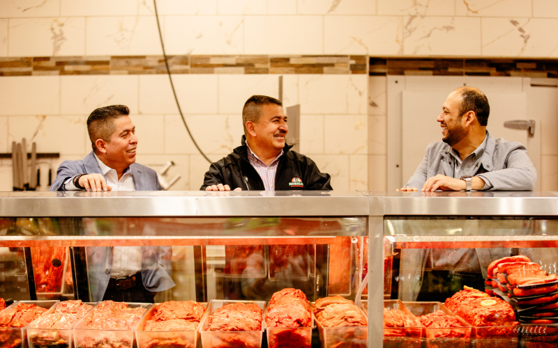 Supermercados Morelos founders behind a butcher counter in their grocery business